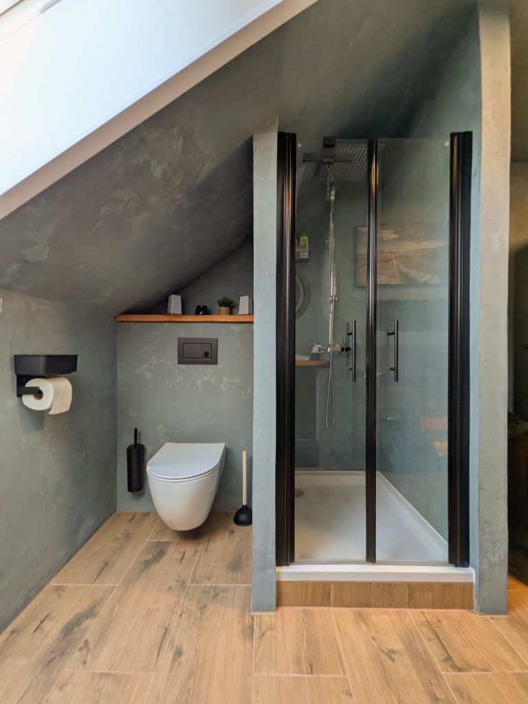 Badezimmer unter der Dachschräge mit Duschkabine in Betonoptik