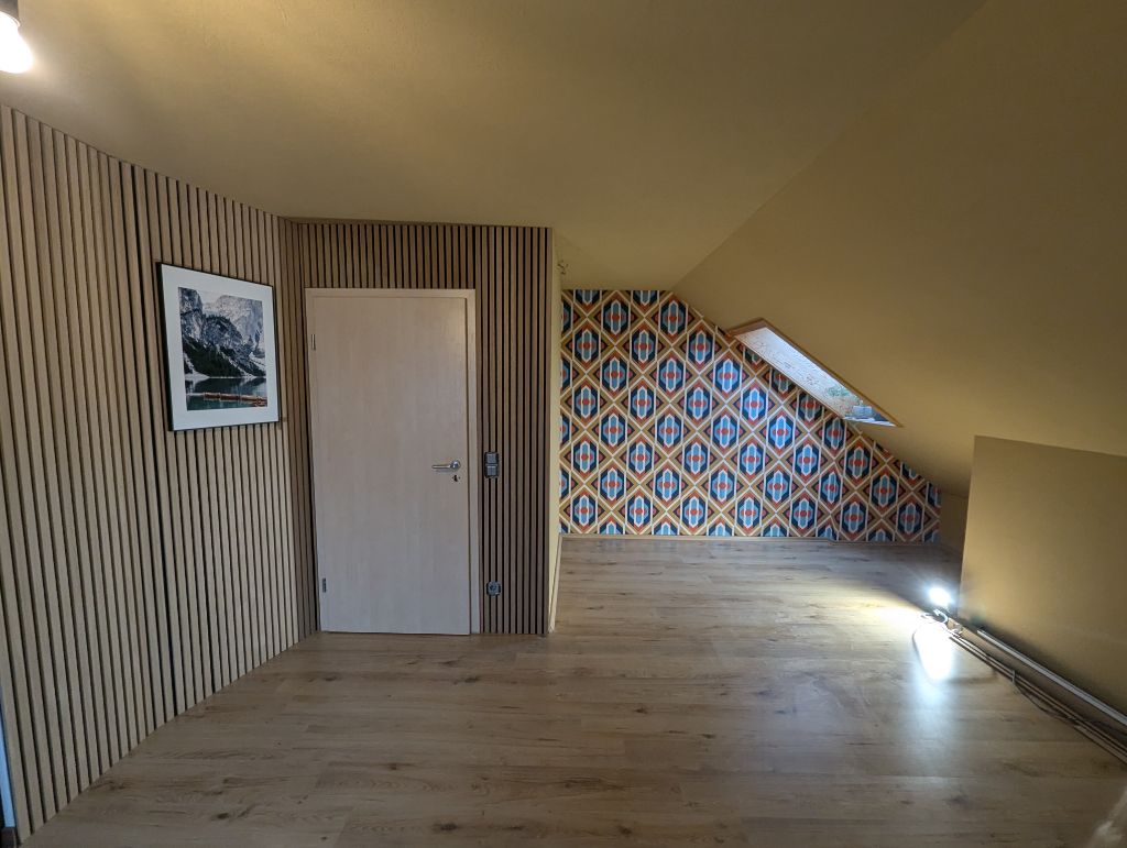Flur nachher mit Holzlamellen-Wandverkleidung und neuer Tapete in der Dachschräge